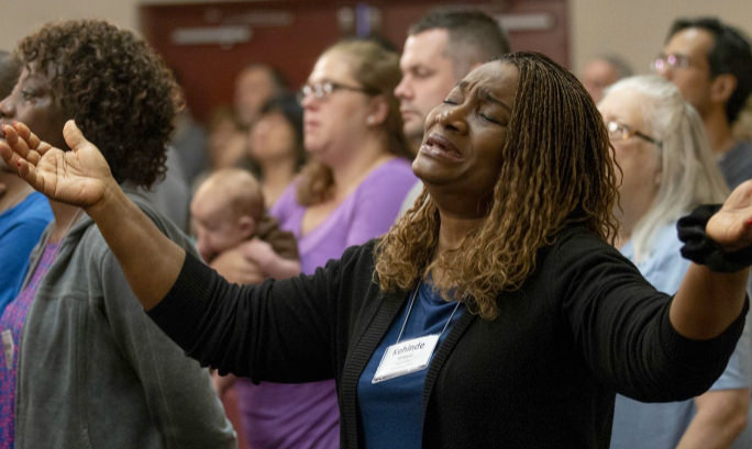 A woman worships with her arms raised.