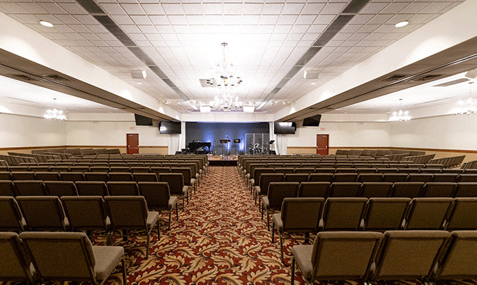 A large meeting space with comfortable seating and a stage at the front.