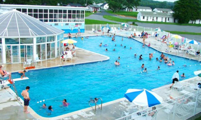 A large L-Shaped pool is filled with swimmers enjoying the water.