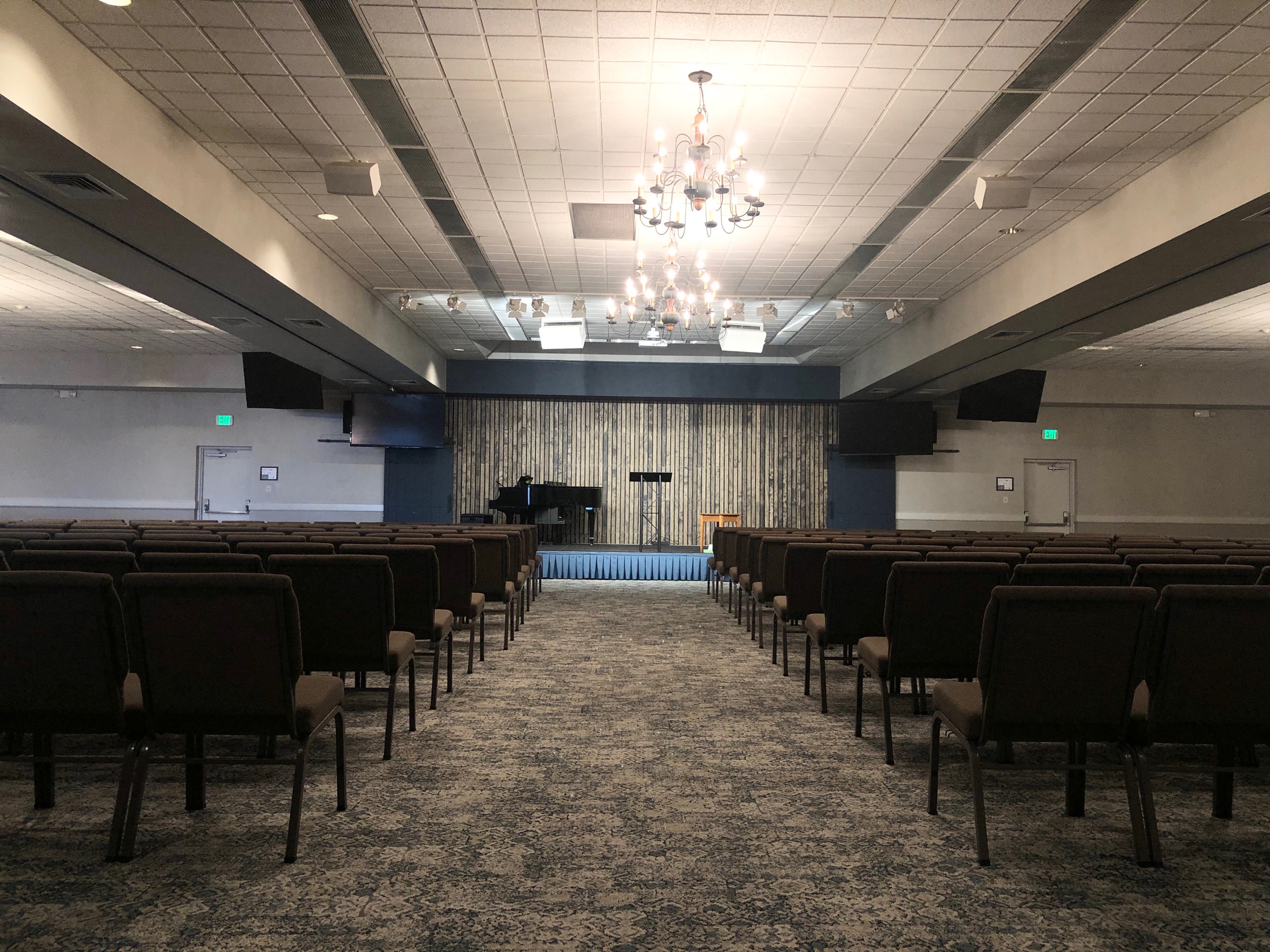 A large meeting space with comfortable seating and a stage at the front.